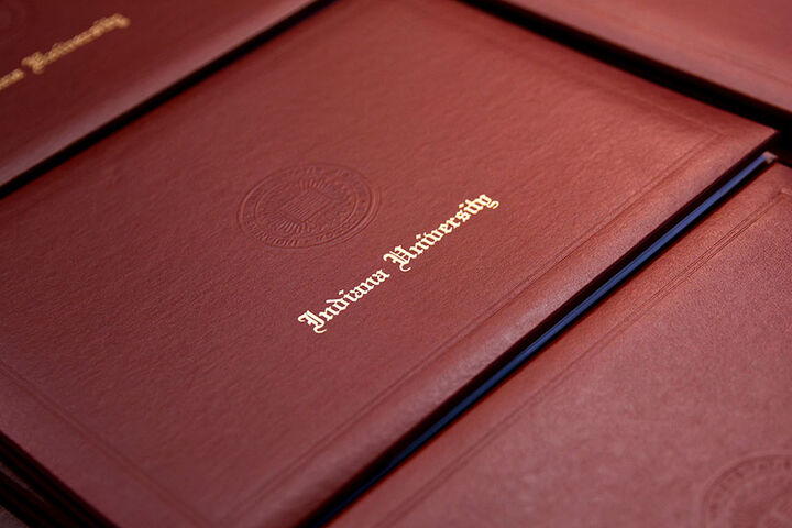 Indiana University diplomas sit in a stack.